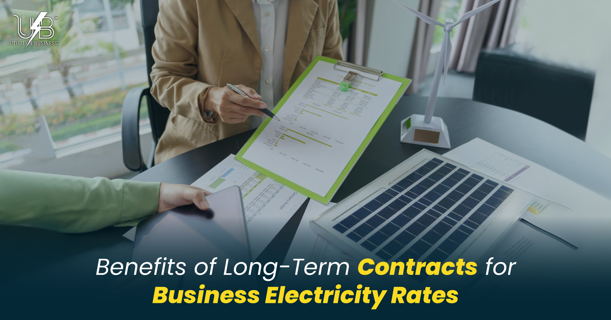 Business consultant reviewing long-term electricity contract rates with client, laptop and wind turbine model on desk